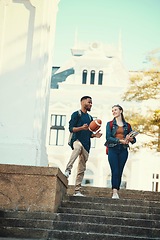 Image showing University, students and friends with a woman and man walking down stairs on campus for education. Learning, books and college with a male and female pupil taking a walk to class for studying