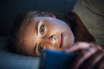 Image showing Night, phone and young woman on sofa to check social media, browsing internet and online content. Technology, mobile app and girl with smartphone for texting, chatting and conversation lying on couch
