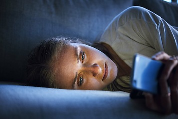 Image showing Phone, night and sad woman relaxing on sofa in living room scrolling on social media after a break up. Depression, upset and girl on couch in lounge reading student loan or debt emails on smartphone.