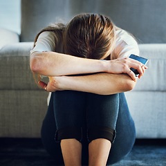 Image showing Sad, depression and woman with phone in living room home after break up message, cyber bullying victim or grief. Mental health, anxiety or depressed female holding 5g mobile smartphone alone in house