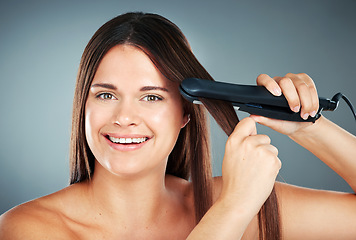 Image showing Beauty, hair care and flat iron with a model woman in studio on a gray background to straighten her hair. Wellness, growth and straight with an attractive young female using a hair straightener