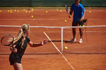 Image showing A professional tennis player and her coach training on a sunny day at the tennis court. Training and preparation of a professional tennis player