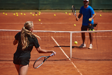 Image showing A professional tennis player and her coach training on a sunny day at the tennis court. Training and preparation of a professional tennis player