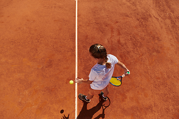 Image showing Top view of a professional female tennis player serves the tennis ball on the court with precision and power