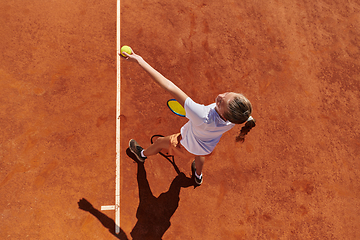 Image showing Top view of a professional female tennis player serves the tennis ball on the court with precision and power