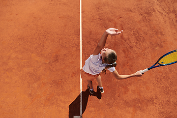 Image showing Top view of a professional female tennis player serves the tennis ball on the court with precision and power