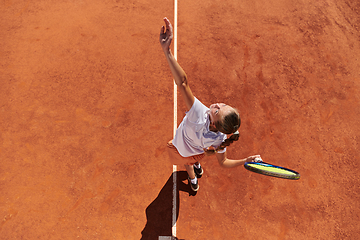 Image showing Top view of a professional female tennis player serves the tennis ball on the court with precision and power