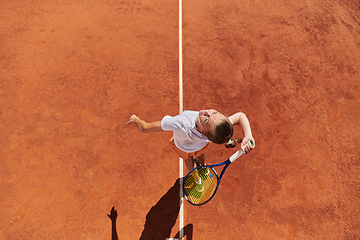 Image showing Top view of a professional female tennis player serves the tennis ball on the court with precision and power