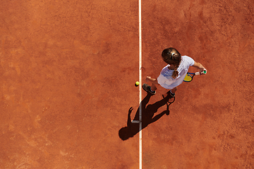 Image showing Top view of a professional female tennis player serves the tennis ball on the court with precision and power