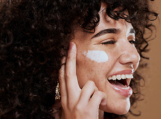 Image showing Cream, woman and skincare for wellness, natural beauty and confident on brown studio background. Cosmetics, female and girl with lotion, smooth face and organic facial with smile, happy and freckles.