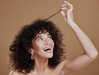 Image showing Hair care, beauty and happy woman with afro in a studio for a health, clean and curly treatment. Wellness, hair style and young model holding strand of natural hair while isolated by brown background