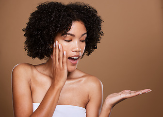 Image showing Skincare, girl and surprise hand product placement with wow, excited and healthy beauty face. Natural, facial and hair care of black woman in brown studio mockup for cosmetics advertising.