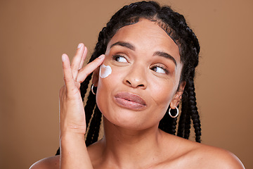Image showing Black woman, skincare and facial moisturizer for beauty cream, makeup or cosmetics against a brown studio background. African American female applying lotion to smooth or hydrate skin for treatment