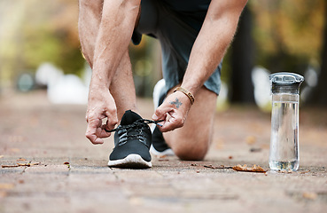 Image showing Fitness, exercise and running shoes while tying shoelace on ground with water bottle for cardio workout or training. Hands of man with sneakers outdoor for run and performance for health and wellness