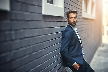 Image showing Fashion, suit and city with a business man or model leaning against a brick wall outdoor for contemporary style. Corporate, executive and trendy with an edgy male posing in the alley of an urban town