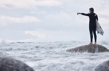 Image showing Man, pointing or surfer on rocks at beach, ocean or rough sea and watching tide, waves or water movement in Hawaii. Sports athlete, surf board or surfing person in fitness, workout or nature training