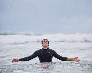 Image showing Surfing, sports and man in ocean during rain enjoy nature, spring weather and swimming in waves. Happiness, raining and young male surfer in sea doing watersports for exercise, training and fitness