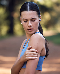 Image showing Woman, earphones and fitness shoulder pain in nature environment workout, sustainability woods training or forest exercise. Runner, sports athlete and arm injury in muscle stress, burnout and crisis