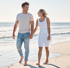 Image showing Holding hands, walking and beach with a young couple on the coast for romance, dating or bonding in summer. Love, travel and walk with a woman and man happy during a walk on the sand together