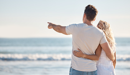 Image showing Couple, love and relax hug on beach with back view for freedom travel vacation or holiday in summer. Ocean, man point and woman on sea sand for romance, quality time and marriage bonding together