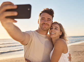 Image showing Phone, selfie and happy couple on the beach on vacation for their romantic honeymoon celebration. Happiness, love and young man and woman taking picture together by the ocean or sea while on holiday.