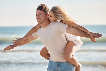 Image showing Couple, freedom and love at the beach, together and piggyback on adventure with travel and ocean. Trust, relationship and man with happy woman, seaside vacation with arms out and care free.