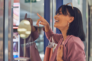 Image showing Happy woman, window and shopping, mall and excited to buy sales, discount products and luxury fashion clothes. Smile customer pointing in glass, shopping mall and choice, decision and retail boutique