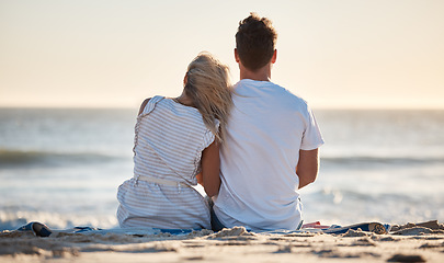 Image showing Beach, love and couple relaxing on the sand while watching the ocean waves together on vacation. Travel, romantic and man and woman on seaside holiday to bond, relax and rest by the sea in Australia.