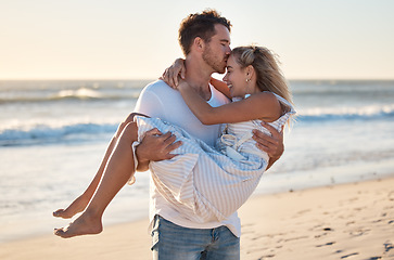 Image showing Kiss, beach and man carrying woman for romantic sunset embrace on Australia holiday in summer. Couple, love and happy man holding partner with care, gratitude and respect on ocean walk.