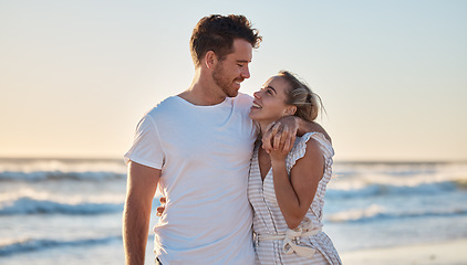 Image showing Sunset beach, love and summer with a couple hug on the sand by the sea or ocean while on holiday together. Happy, smile and romance with man and woman bonding while on travel vacation or break at sea