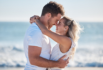 Image showing Couple, love and hug at the beach together, nose touch and bonding with travel and date by the ocean for summer holiday. Happy, man and woman with quality time, sea waves and romantic out in nature.