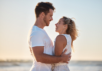 Image showing Couple, travel and hug with love and beach holiday, romantic vacation and happy together at sunrise. Man, woman and care with adventure by the ocean, outdoor and nature for bonding and romance.