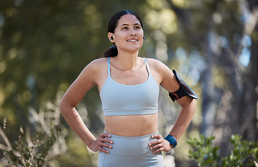 Image showing Woman, earphones and fitness arm band in nature park break, garden or sustainability environment for exercise, training or workout. Smile, happy or resting runner listening to music or health podcast