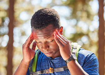 Image showing Headache, stress hiking with a black man athlete holding his temples in pain while walking in the forest. Nature, fitness and migraine with a male hiker in the woods for exercise or training