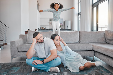 Image showing Tired, parents and child jump on sofa with exhausted mother and father sitting on floor in living room. Family, energy and young girl jumping on couch with frustrated, annoyed and upset mom and dad