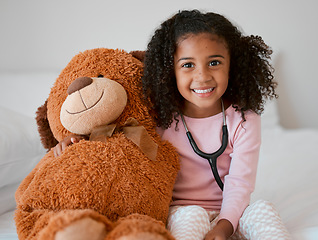 Image showing Stethoscope, teddy bear and girl with a child her stuffed animal with a smile in her house. Portrait of happy female kid holding a fluffy toy, learning to be a doctor or pediatrician in healthcare