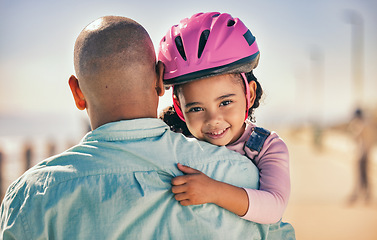 Image showing Father, bicycle and girl portrait of a young kid with a helmet by the sea ready for cycling learning. Family, holiday and fun of a dad and child hug with happiness and bike gear excited for activity