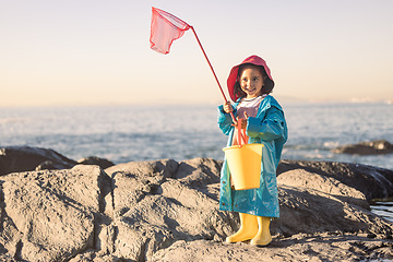 Image showing Child, girl or kid fishing net or bucket by beach rock pools, ocean or sea for salt water shrimp, muscles or crabs on summer holiday. Smile, happy or youth and fisherman equipment in Brazilian nature