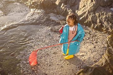 Image showing Fishing, net and girl on an adventure at the beach with smile, happy and travel by the ocean in Spain. Nature, playful and child catching rocks by the sea on holiday for peace, relax and happiness