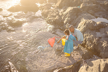 Image showing Father, kid and fishing net at beach, ocean and sea for learning, development and adventure, summer holiday and sunshine vacation. Girl child catching fish with parent in nature, rock pool and water