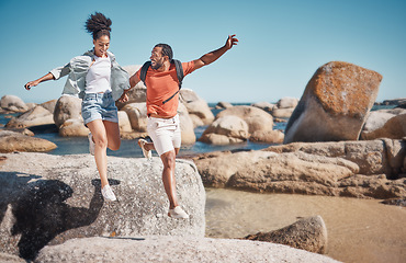 Image showing Black couple, fitness and beach while on vacation taking a jump or leap from a rock for travel, adventure and exercise in summer. Happy man and woman together at sea for quality time on holiday