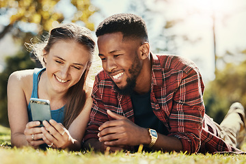 Image showing Interracial, couple and phone social media in park to relax, bond and smile together in Los Angeles. Technology, streaming and happy people enjoy summer in nature with mobile app entertainment.