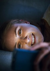 Image showing Woman, phone or lying on sofa at night in house or home living room on online dating app, social media or internet esports game. Smile, happy or relax student on mobile technology social network news