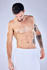 Image showing Body, health and man in towel in studio after shower, cleaning or bathing for hygiene and wellness isolated on a gray background. Topless, body art and male fitness model with tattoos, abs and muscle