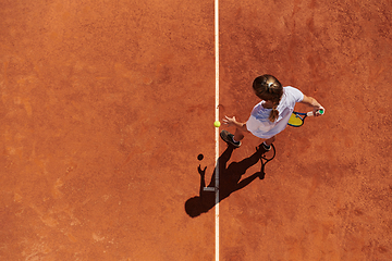 Image showing Top view of a professional female tennis player serves the tennis ball on the court with precision and power