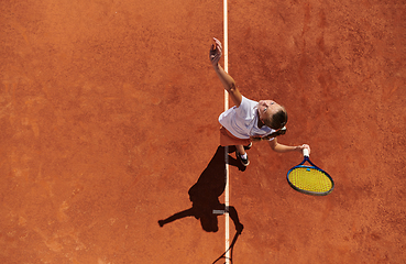 Image showing Top view of a professional female tennis player serves the tennis ball on the court with precision and power