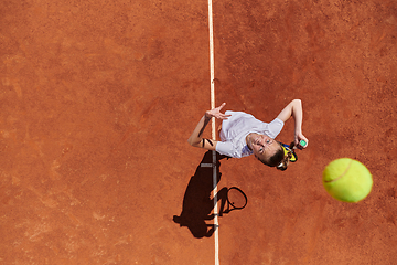 Image showing Top view of a professional female tennis player serves the tennis ball on the court with precision and power