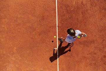 Image showing Top view of a professional female tennis player serves the tennis ball on the court with precision and power