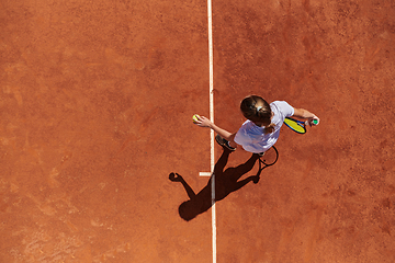 Image showing Top view of a professional female tennis player serves the tennis ball on the court with precision and power