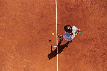 Image showing Top view of a professional female tennis player serves the tennis ball on the court with precision and power